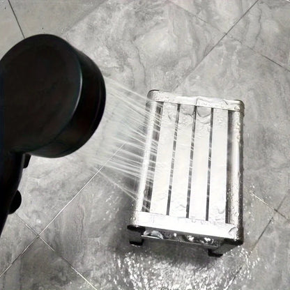 Metallic shower head spraying water onto a metal tray on a tiled floor.